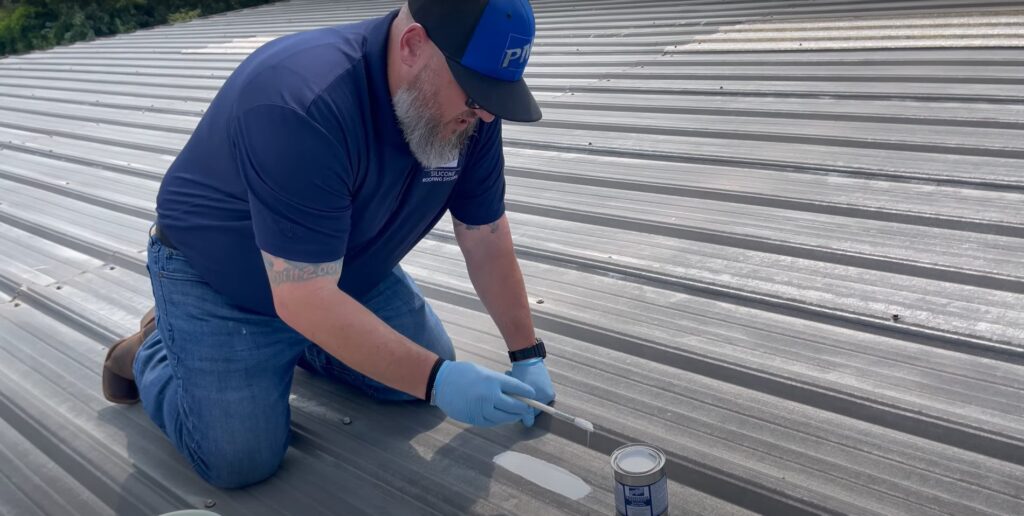 Jeff Romero applies coating to a metal roof while administering an adhesion test.